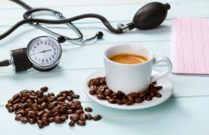 فنجان قهوه و دان قهوه کنار دستگاه فشار خون